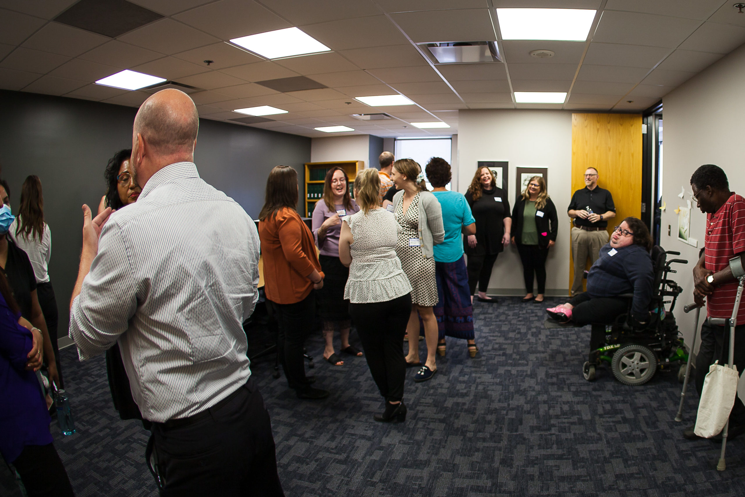 Group of individuals stand around in a conference room. Each one is talking to another person in the room, sometimes groups of people during an event at DRI.