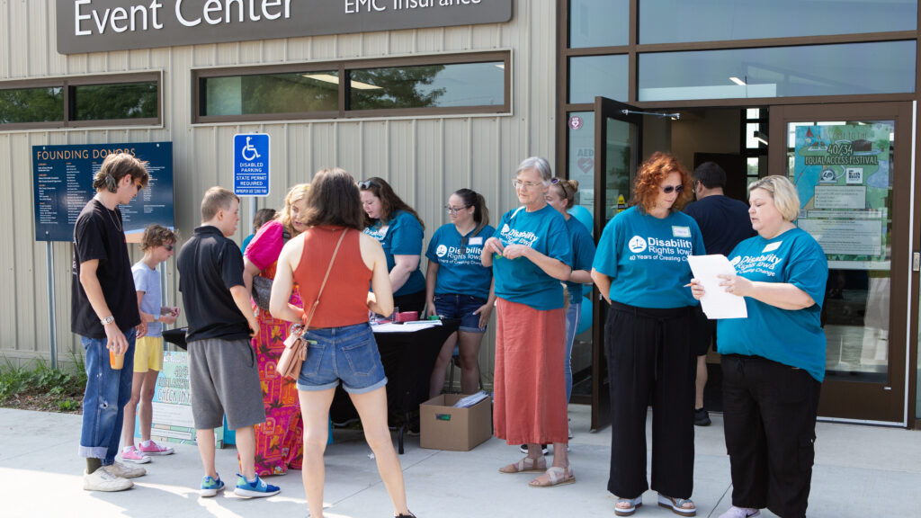 DRI employees and Iowans with disabilities wait outside a building registering for an event
