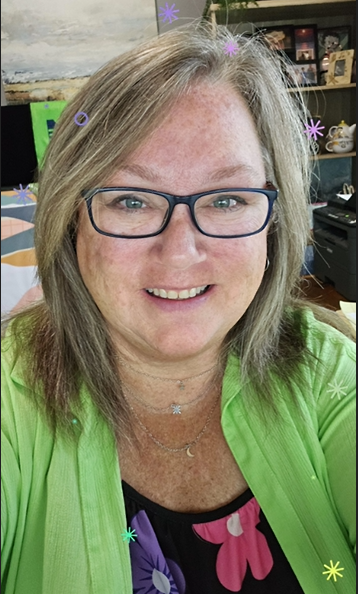 White woman with greyish blonde hair and glasses wears a bright green shirt and smiles at the camera.